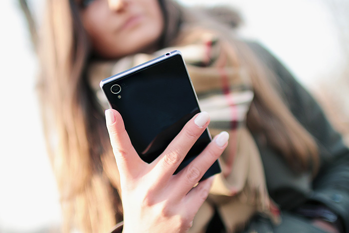 A young woman holds a smartphone in her hand